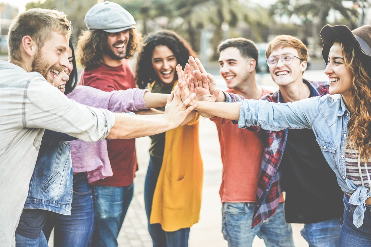 Young millennials friends stacking hands together - Happy students celebrating together - Youth lifestyle, university, social trends, relationship and friendship concept - Focus on hands