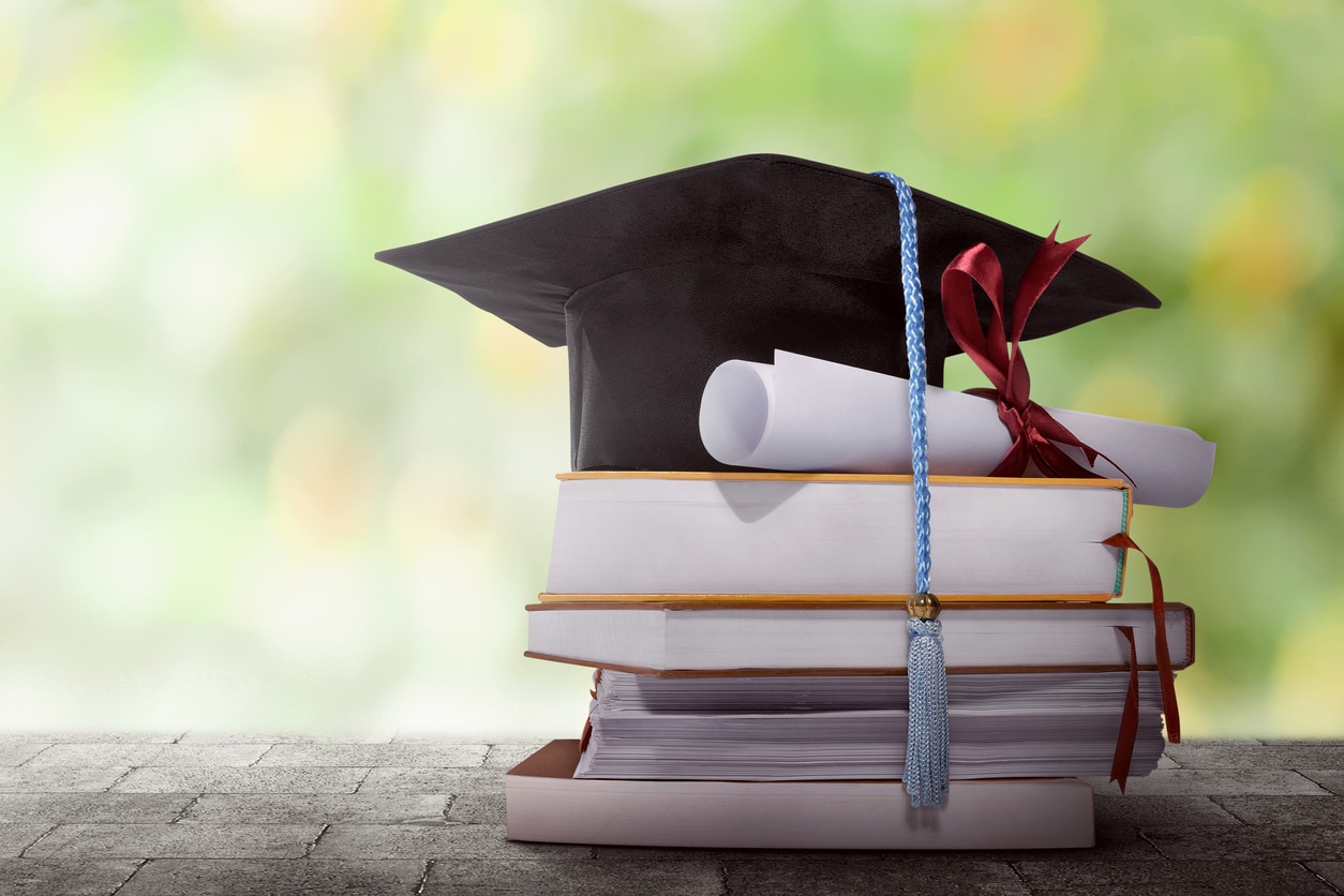 Graduation hat with degree paper on a stack of book